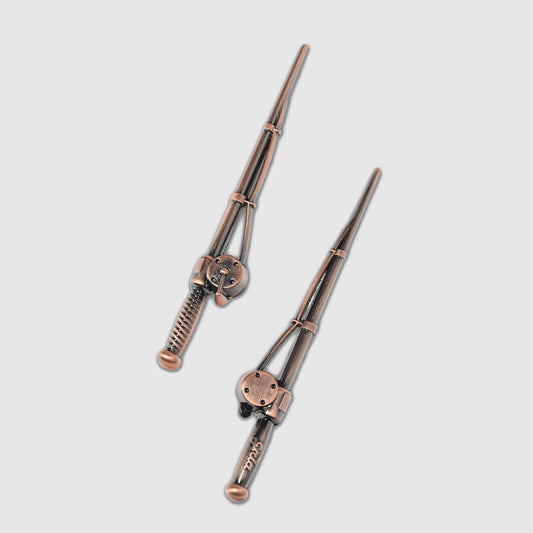 Two metal hair sticks inspired by the design of Guerrilla Golf’s Fishing Pole Divot Tool, each featuring intricate hilts and subtle locking mechanisms—displayed diagonally against a simple light background, these stylish accessories are crafted with the same precision as classic golf divot tools, offering an elegant yet unexpected tribute to iconic gear from the Guerrilla Golf collection.