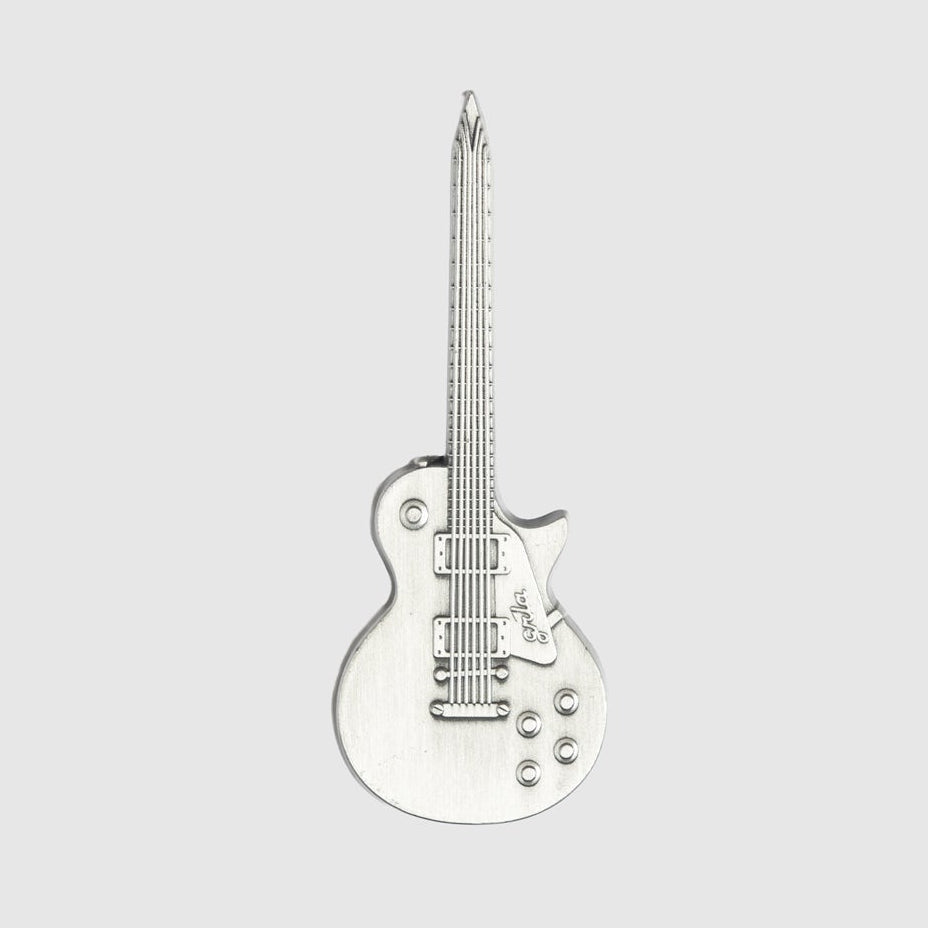 A silver Guerrilla Golf Guitar Divot Tool, shaped like a guitar with realistic details such as strings, knobs, and pickups—resembling a stylish pen—displayed vertically on a plain light gray background.