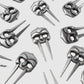 A repeating pattern of Gladiator Divot Tool designs by Guerrilla Golf, featuring silver metallic masks with long, pointed jaw extensions and red gem details evocative of golf accessory precision, displayed on a light gray background.