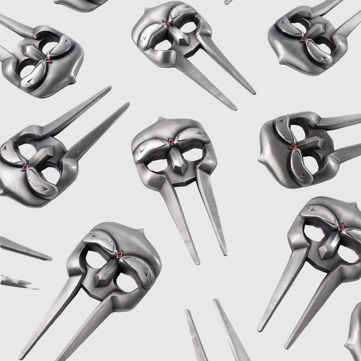 A repeating pattern of Gladiator Divot Tool designs by Guerrilla Golf, featuring silver metallic masks with long, pointed jaw extensions and red gem details evocative of golf accessory precision, displayed on a light gray background.
