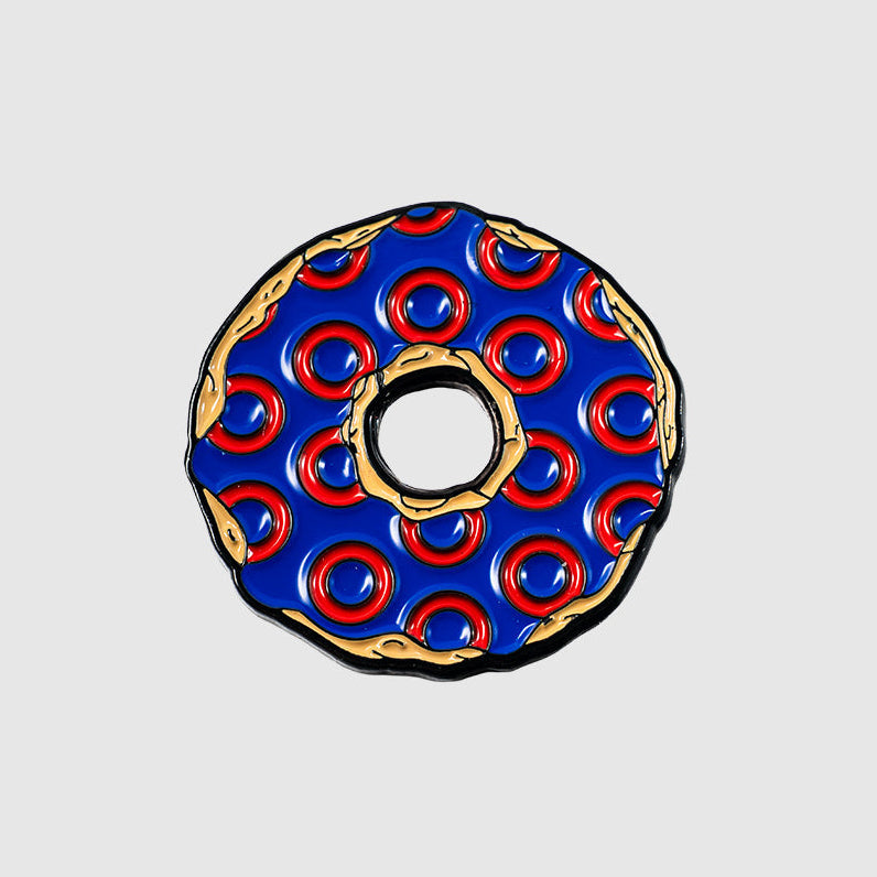 The Guerrilla Golf Donut Ball Marker, featuring a donut shape with blue frosting and red circular patterns outlined in gold, is displayed against a plain light gray background.