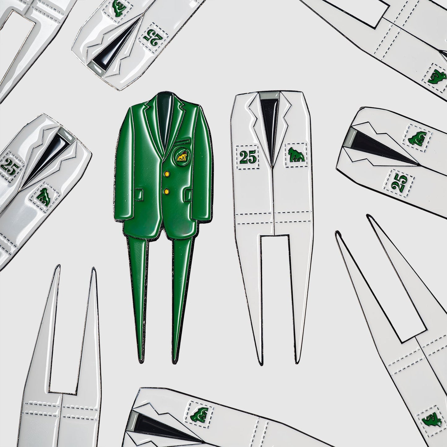 A green Caddy divot tool by Guerrilla Golf, shaped like a jacket and the perfect golf accessory or gift, is surrounded by white jacket-shaped Caddy divot tools adorned with golf-themed patches and numbers, all displayed on a white background.