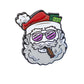 Santa the Degenerate Ball Marker by Pins and Aces features a cartoon Santa head with pink sunglasses, a red hat with money, and a cigar. Great as a quirky Christmas golf accessory or Santa golf ball marker. White background with shadow below.