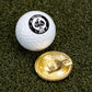A white golf ball with a black Pins and Aces logo rests beside the Dogecoin Ball Marker—a shiny, gold chrome token—on green artificial grass.