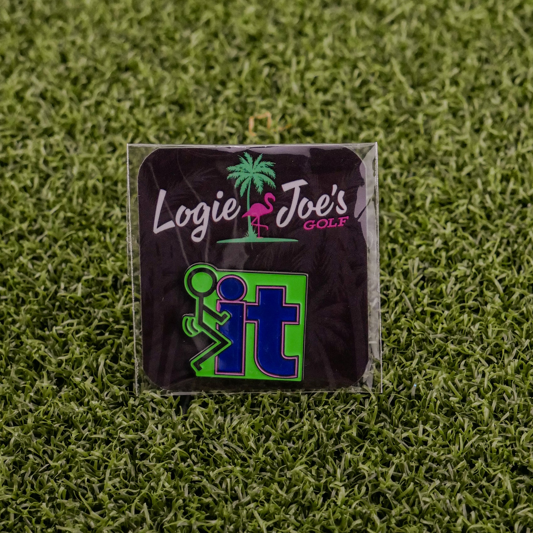 The “F” It golf ball marker from Ballmarkers by Logie Joe’s features a cartoon figure kicking the word It on grass, adding a humorous touch to your collection.