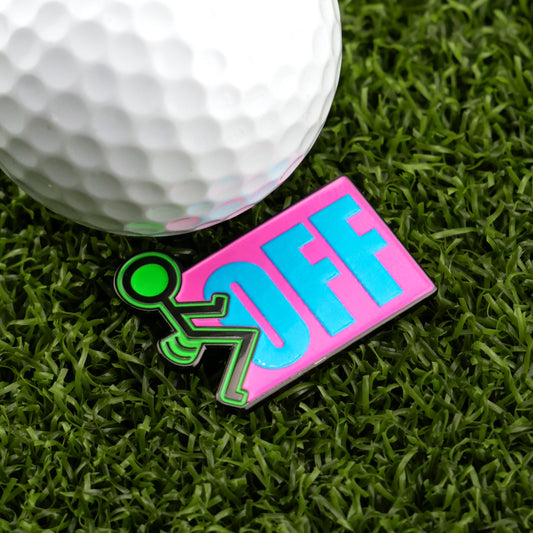 A golf ball rests on artificial grass beside Logie Joe's Golf “F” Off Ball Marker—a playful pin with a green stick figure pushing the word OFF in bold blue letters on pink—perfect for anyone seeking funny golf gifts.