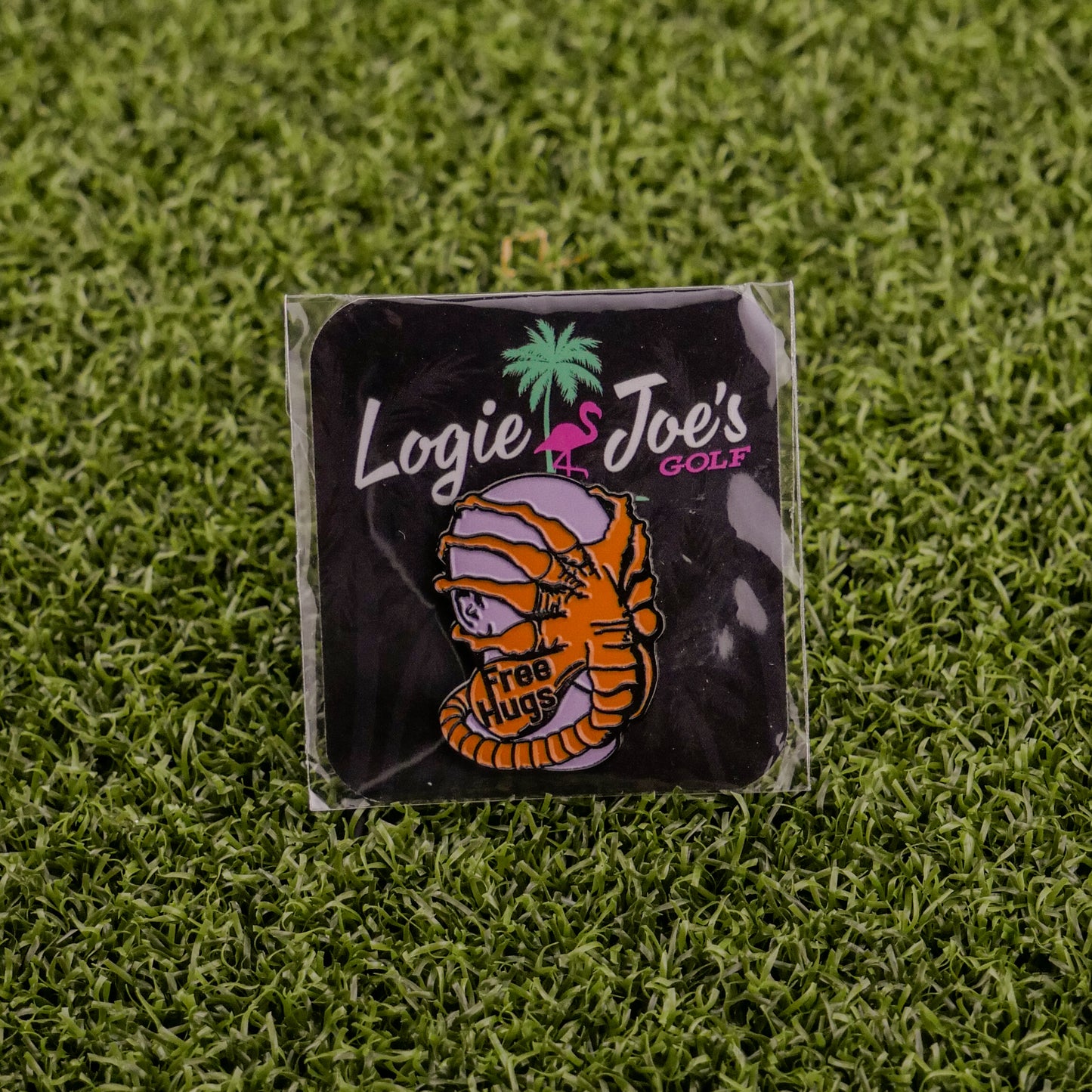 Face Hugger by Ballmarkers from Logie Joe’s is a small pin and premium ball marker featuring a mummy with a “Free Hugs” sign on grass. Packaged with Logie Joe’s branding, it adds fun and uniqueness to your golf gear.