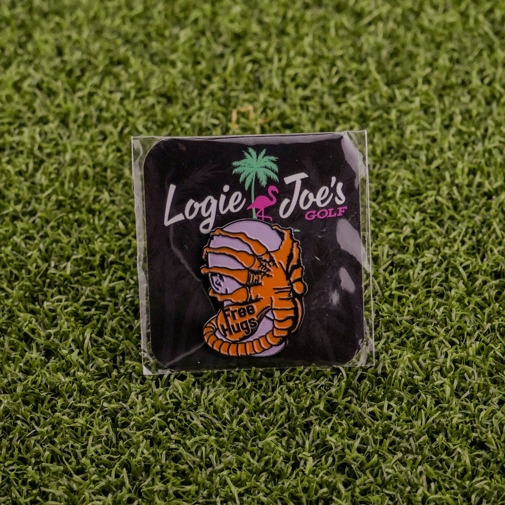 Face Hugger by Ballmarkers from Logie Joe’s is a small pin and premium ball marker featuring a mummy with a “Free Hugs” sign on grass. Packaged with Logie Joe’s branding, it adds fun and uniqueness to your golf gear.