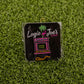 The Florida Man (Game Over) enamel pin by Logie Joe's Golf features an arcade machine with Florida Man, Game Over text, a flamingo, and palm tree on artificial grass—a funny golf accessory that doubles as a unique ball marker.