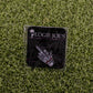 The “F” Your Feelings pin from Logie Joe's Golf, featuring a skeleton hand gesture, is displayed on branded card atop artificial grass—a standout golf ball marker or unique gift for fans of bold golf accessories.