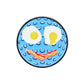 Logie Joe's Golf "Breakfast Ball" is a blue, textured smiley face ball marker with fried egg eyes and a bacon strip mouth on a plain white background—a playful, premium choice for unique golf accessories.