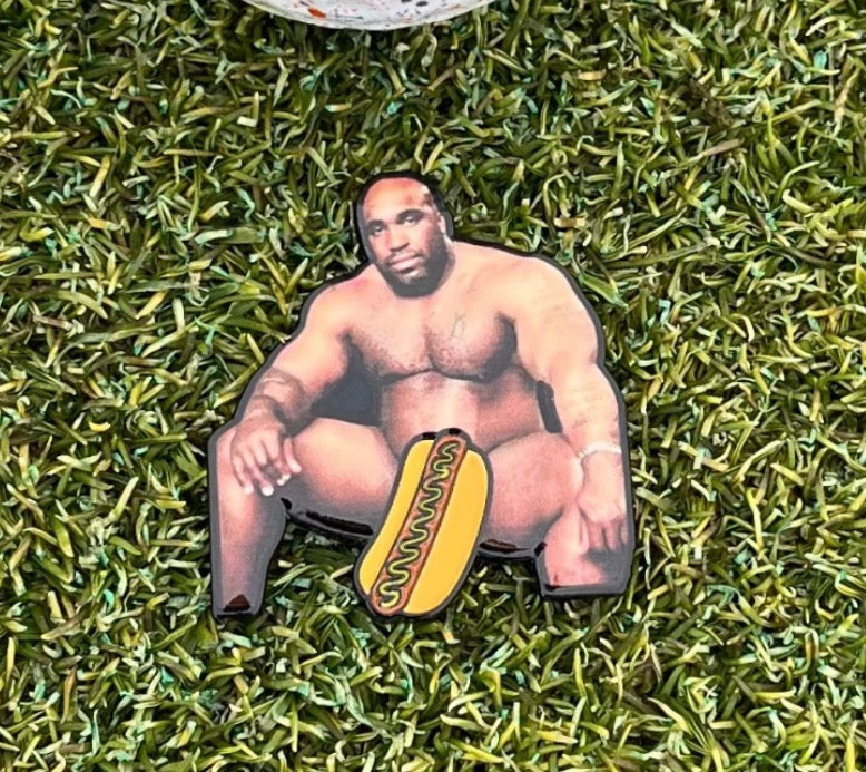 Show your sense of humor on the green with the Big Glizzy Ball Marker from Tee Bumps—a playful golf accessory featuring a muscular man sitting nearly nude on artificial grass, cleverly covered with a cartoon hot dog for an eye-catching look. This fun and bold legend tribute is sure to be a conversation starter at your next round.