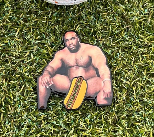 Show your sense of humor on the green with the Big Glizzy Ball Marker from Tee Bumps—a playful golf accessory featuring a muscular man sitting nearly nude on artificial grass, cleverly covered with a cartoon hot dog for an eye-catching look. This fun and bold legend tribute is sure to be a conversation starter at your next round.