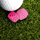 The Pink Fuzzy Dice Ball Marker by Ballmarkers.com rests on green artificial grass beside a white golf marker.
