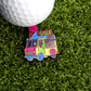 The Golf Cream Truck Ball Marker by Ballmarkers.com features a colorful enamel ice cream truck with a GOLF SHOP sign, displayed on green turf next to a white golf ball—a nostalgic and playful golf accessory.