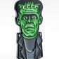 The Frankenstein Ball Marker by Pins and Aces is a premium, colorful enamel golf accessory featuring a stylized bust of Frankenstein’s monster with green skin, black hair, and a dark jacket on a white background.