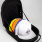 The Pins and Aces Hat Caddie, shown partially open in black, holds several colorful baseball caps, with a white cap featuring a spade logo on top; its interior displays a spade-shaped imprint.