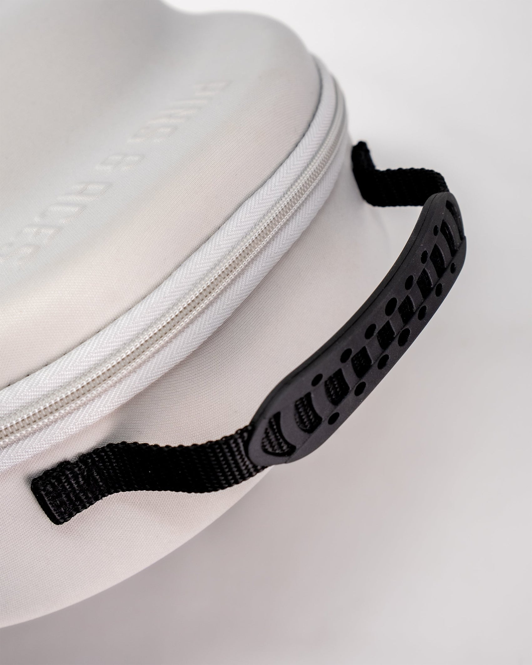 A close-up of the Pins and Aces Hat Caddie, a white golf hat case featuring a textured black handle and black strap, set against a plain white background.