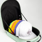 The Pins and Aces Hat Caddie, shown open on a white background, is a mint green case embossed with the brand’s name, neatly storing several colorful caps with a white spade logo hat on top.