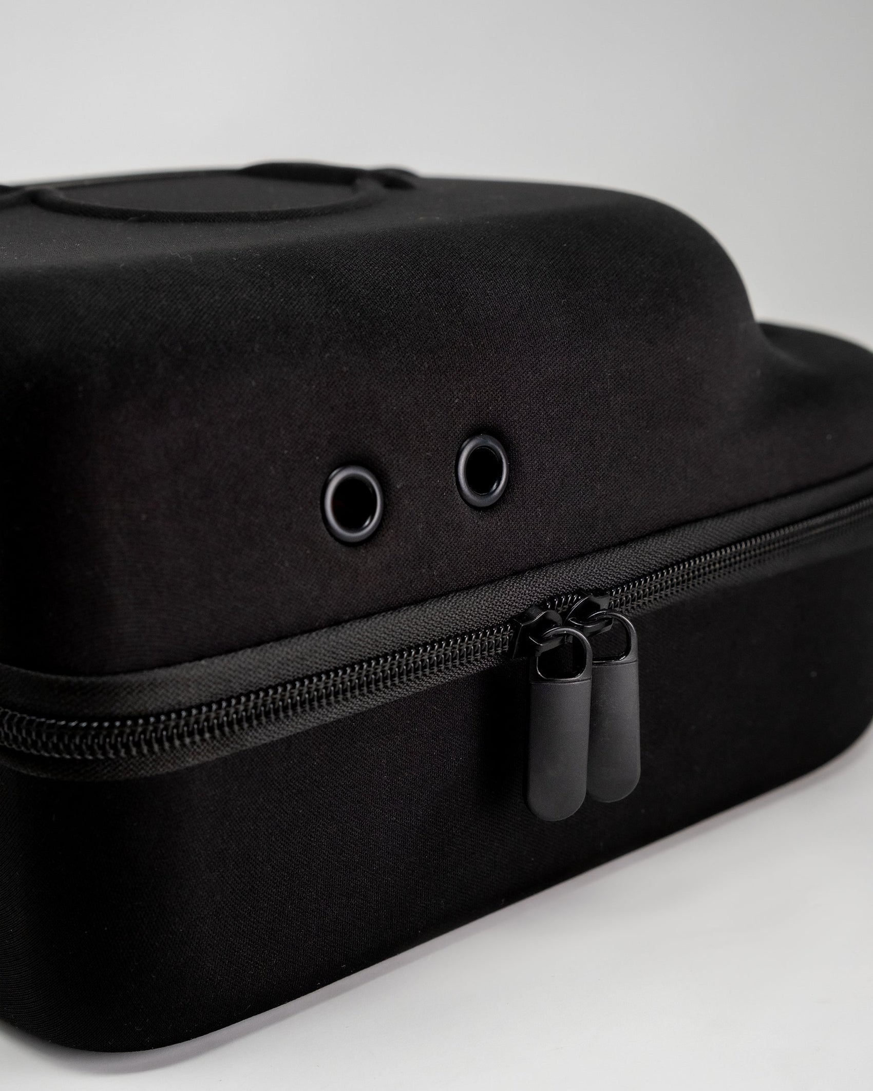 A close-up of the Pins and Aces Hat Caddie, a black zippered carrying case with two grommet holes on top, shown against a plain white background.