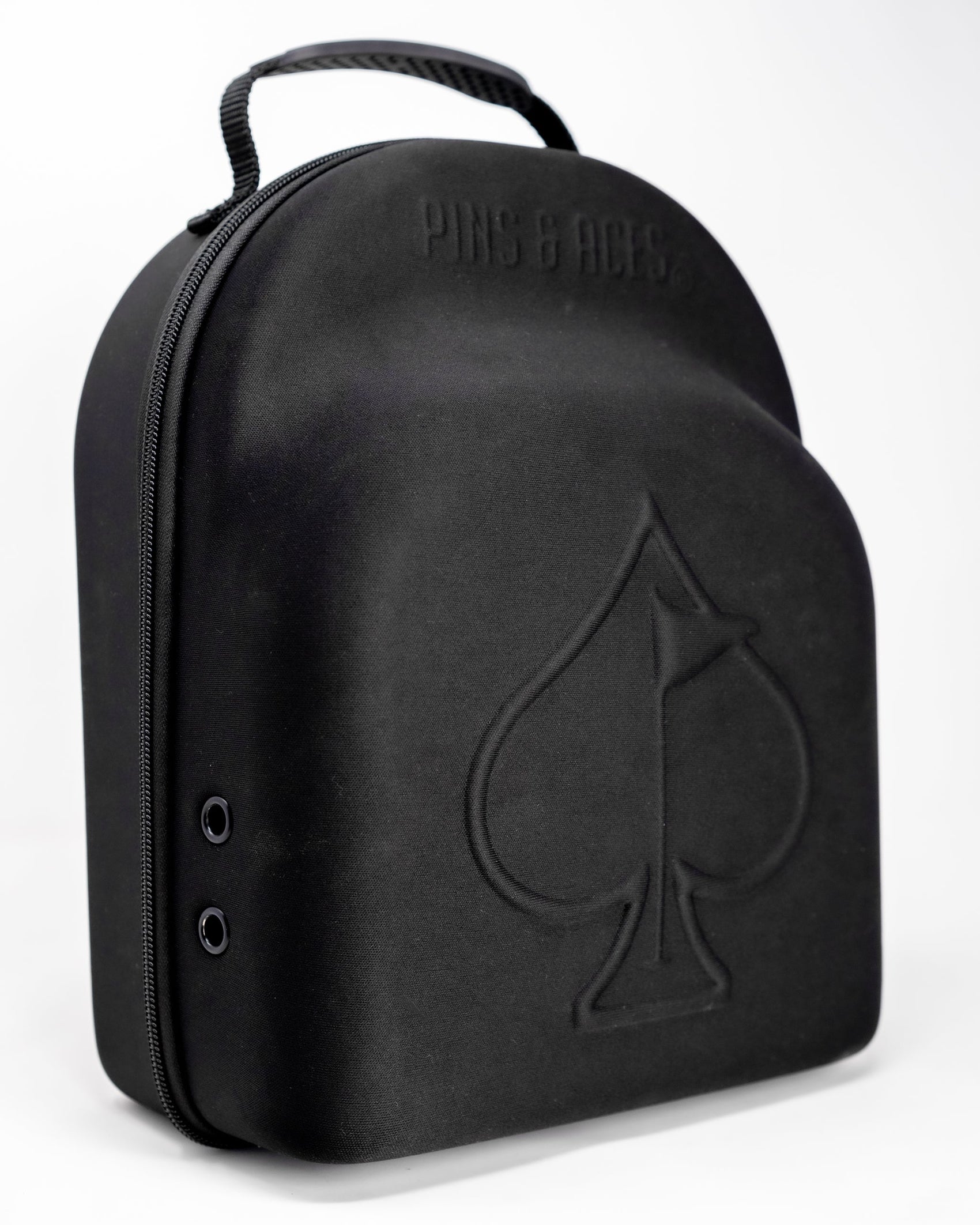 A black Hat Caddie by Pins and Aces, featuring a handle, zip closure, and a large spade symbol with "Pins and Aces" embossed on top, shown against a plain white background.