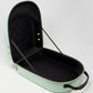 The Pins and Aces Hat Caddie, in light green, opens to reveal a black interior with an embossed spade symbol and elastic lid straps. Featuring a black handle and silver hardware, it keeps your hats secure and stylish on the go.