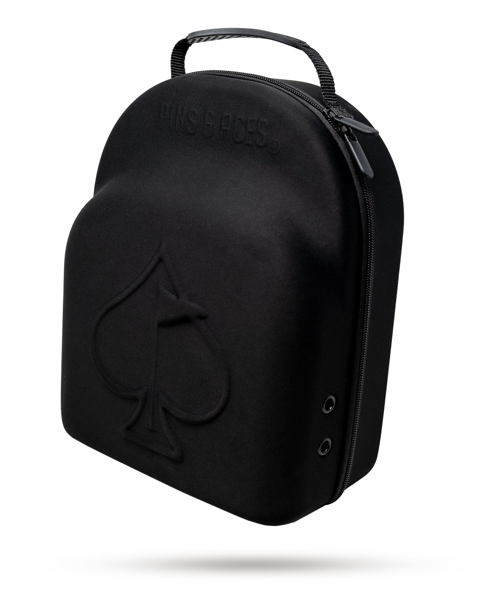The Pins and Aces Hat Caddie is a black, hard-shell golf hat case with a handle, featuring an embossed spade symbol and "PINS & ACES" on the front. Zipped closed, it's stylishly displayed against a white background.
