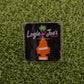 The Hitten Trees Orange Slice air freshener from Ballmarkers.com, shaped like an orange tree and featuring the Logie Joes Golf logo, is a funny golf accessory shown on artificial green grass.