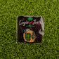 The "Hold That Grenade" pin by Logie Joe's Golf shows a hand with HOLD THIS gripping a grenade, set on artificial grass with a brand card—an edgy addition to any premium golf accessory or unique ball marker collection.