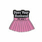 The Does Your Husband Play? Ball Marker by Logie Joe's Golf is a pin shaped like a pleated pink skirt with a black waistband and playful text—a fun golf gift that doubles as a premium ball marker for any golfer.