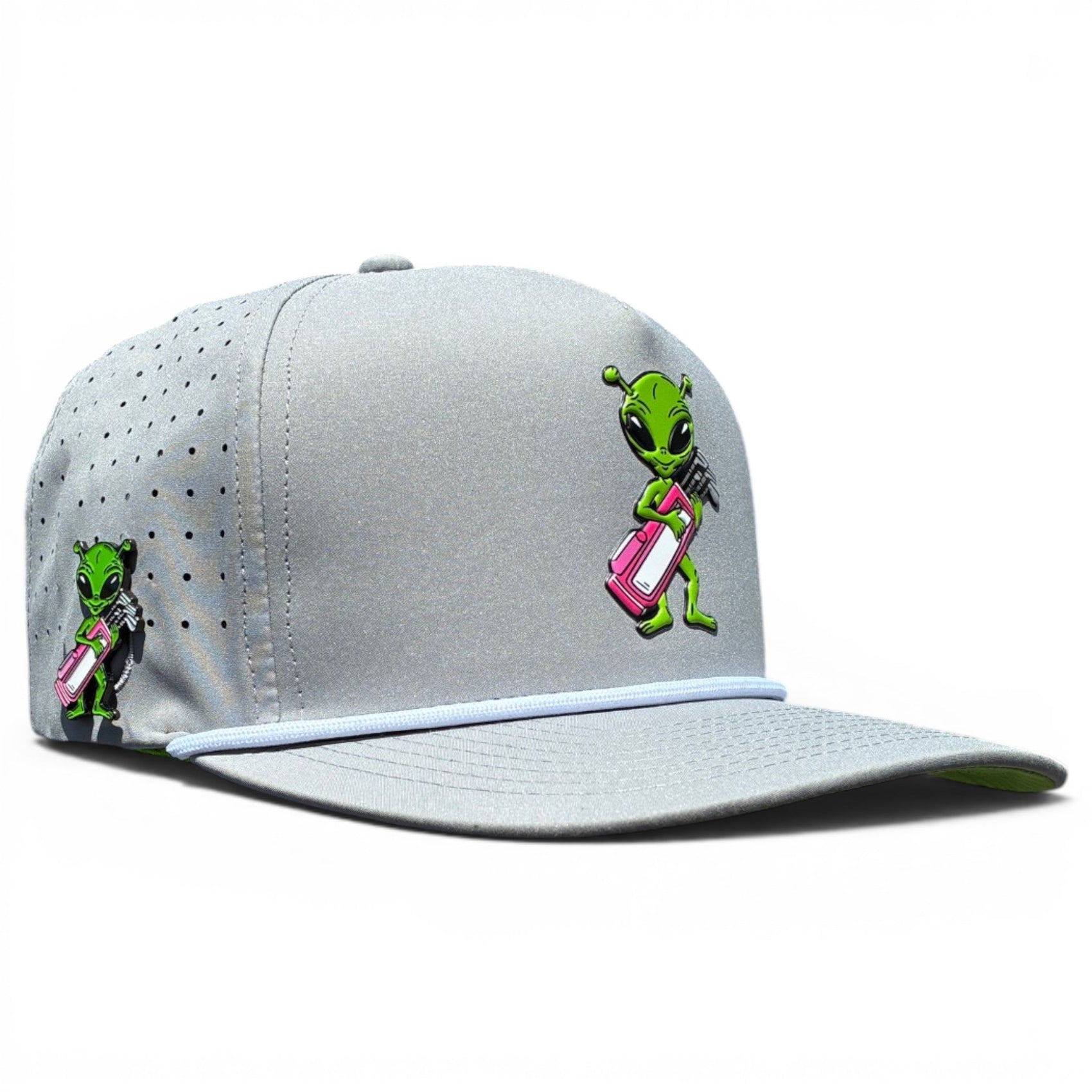 The Logie Joe's Golf Alien Caddy Golf Hat is a light gray adjustable snapback with ventilation holes, an embroidered green alien holding a pink golf bag, and a built-in magnetic ball marker holder—marker included.
