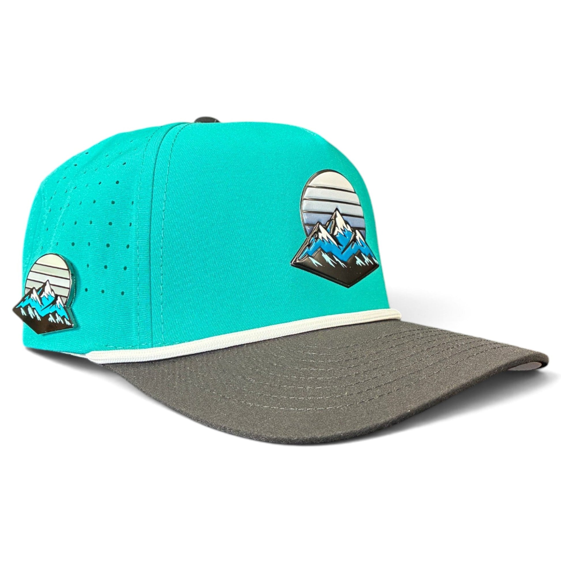 Introducing the Mountain Moonrise Golf Hat from Logie Joe’s Golf—a turquoise and gray adjustable snapback cap featuring a striking mountain and sunset patch on both the front and side. Designed for outdoor play, this hat includes small ventilation holes, a white trim above the brim, and comes equipped with a built-in magnetic ball marker holder plus a marker for enhanced convenience on the course.