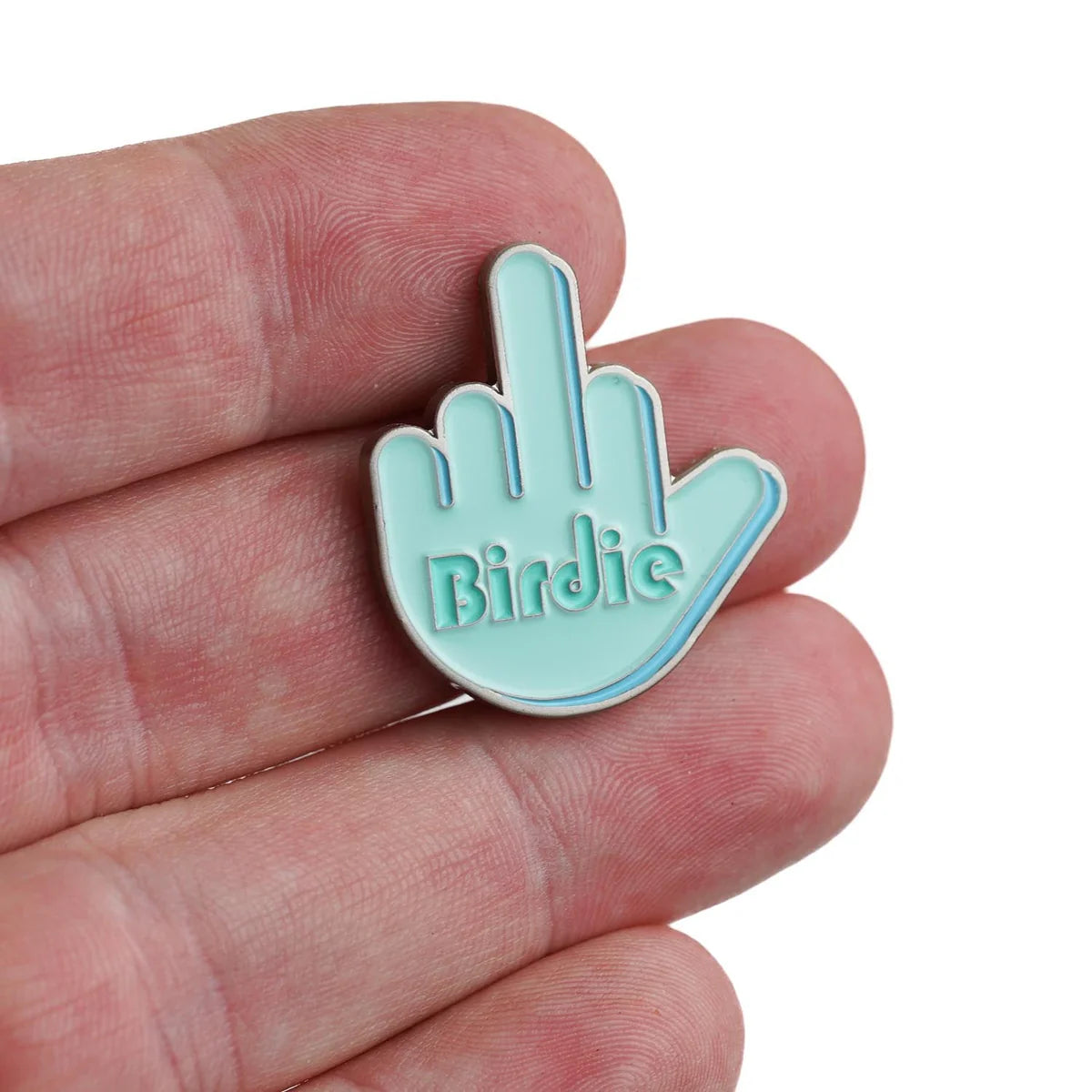 A hand holds Bogey Bros' Birdie Finger pin—light blue, shaped like a hand giving the middle finger, with "Birdie" on the palm—a cheeky accessory to show your attitude on the golf course.
