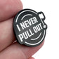 A hand holds the Bogey Bros "I Never Pull Out" round black pin with white text and a small golf flag icon, referencing the golf trend of leaving the flag stick in while putting.