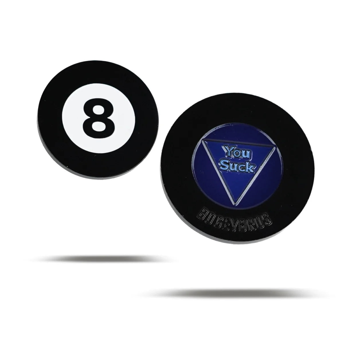 Two round black chips from Bogey Bros are shown on a white background—one is a Magic 8 Ball, the other features a blue triangle with "You Suck" and "GAMERSKIDS" embossed below. Both have faint shadows, making them perfect quirky novelty gifts.