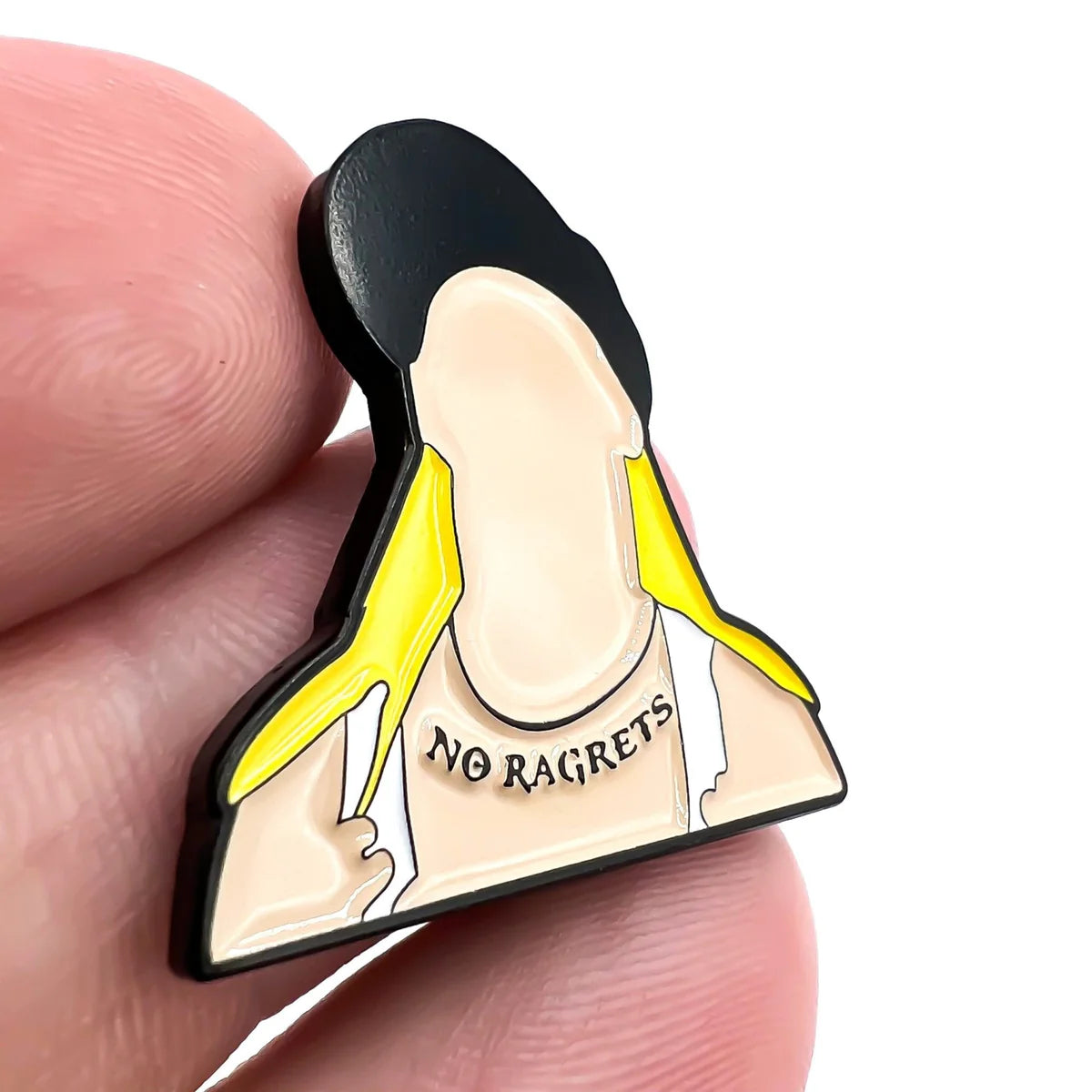 A hand holds the Bogey Bros "Scotty P" enamel pin, featuring a faceless figure with long yellow hair and a tank top that says NO RAGRETS—a funny novelty gift.