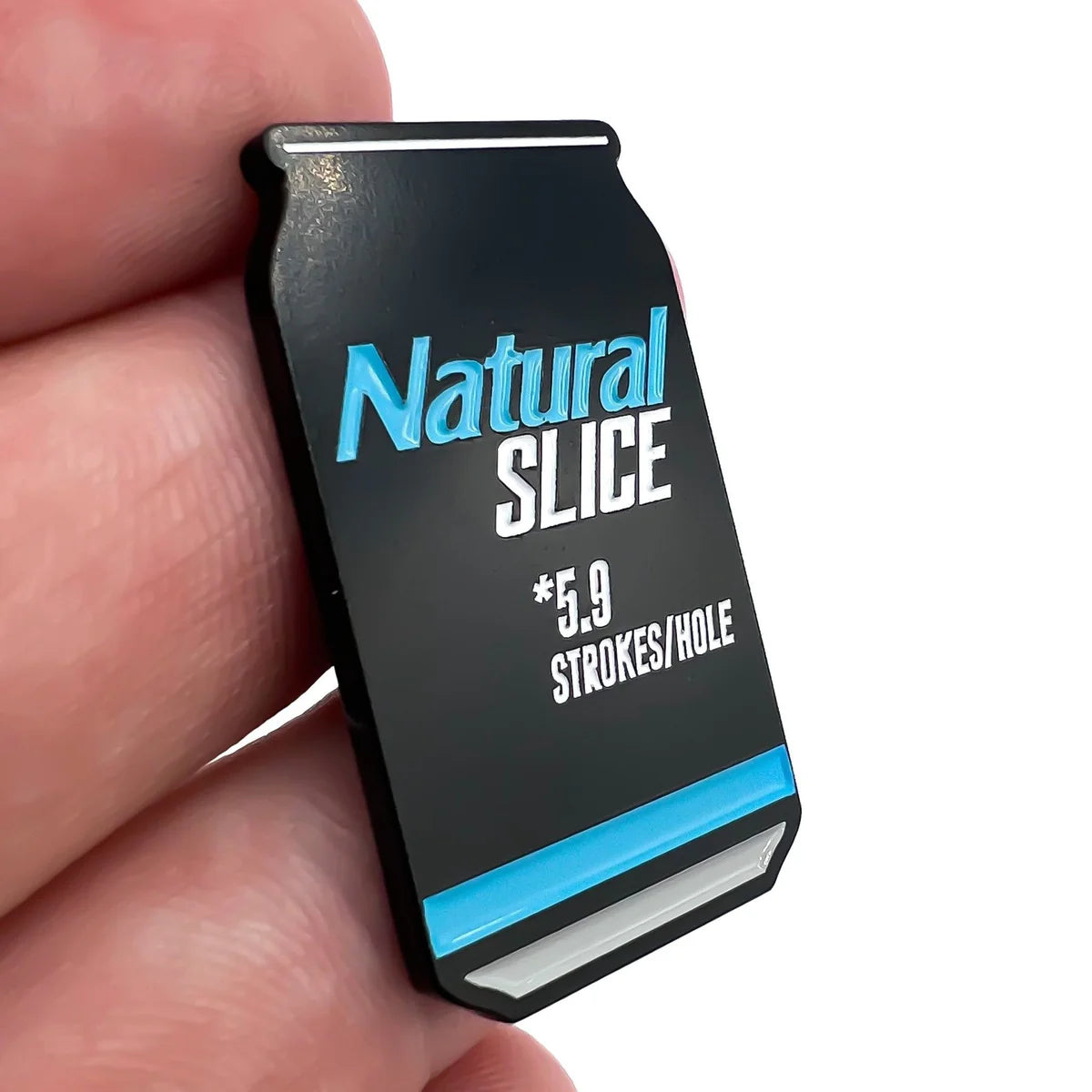A golfer's hand holds a black Bogey Bros Natural Slice ball marker shaped like a can, displaying blue and white text saying "Natural SLICE *5.9 STROKES/HOLE" and featuring a bold blue stripe near the bottom.