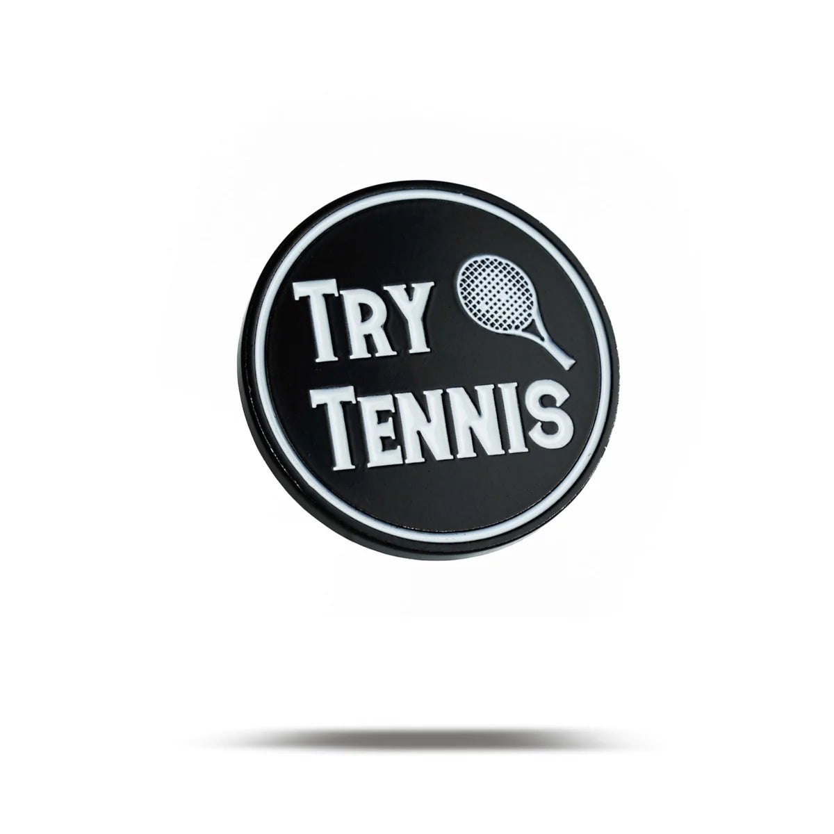A round black Bogey Bros "Try Tennis" pin features white text and a tennis racket illustration above "TENNIS"—a perfect accessory for anyone eager to explore the sport.