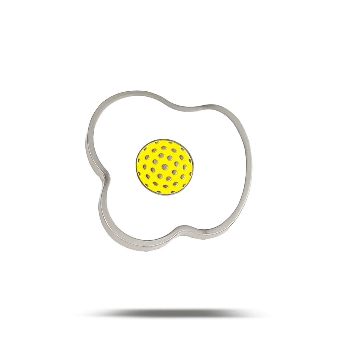 The Bogey Bros Fried Egg is a metal egg ring shaped like a fried egg, with a round yellow center featuring small holes, shown against a white background with a subtle shadow—ideal for breakfast perfection.