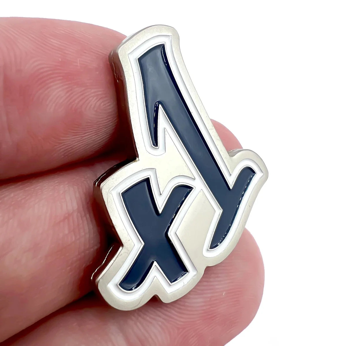 A hand holds a metallic "+1" pin by Bogey Bros in dark blue with a white and silver outline, set against a white background—perfect for those who love big numbers and bold statements.