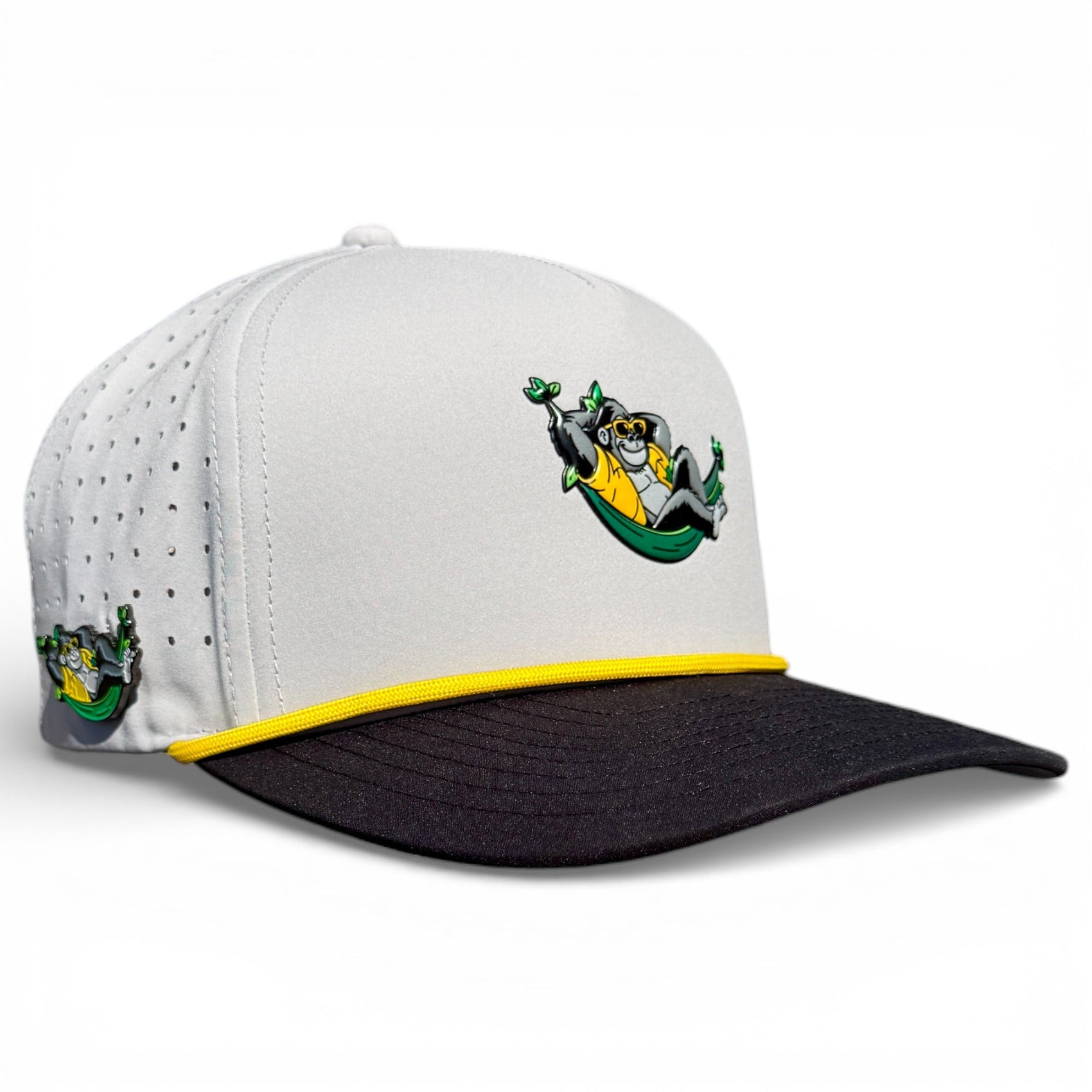 Logie Joe's Golf Banana Hammock Golf Hat: a snapback cap featuring a cartoon monkey in a green hammock, yellow trim, and black brim. Adjustable, with built-in magnetic ball marker holder and marker included. One size fits most.