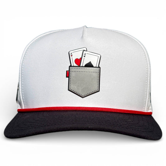 The Pocket Aces Golf Hat by Logie Joe’s Golf is a stylish gray and black snapback cap with a magnetic ball marker holder, featuring pocket aces artwork—perfect for every golfer. Adjustable fit; marker included.