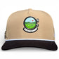 The Logie Joe's Golf Hunting Birdies Snapback Cap is adjustable in tan and black, featuring a round golf course emblem with a red flag, “HUNTING BIRDIES” text, a black brim with white stripe, and built-in magnetic ball marker with marker included.