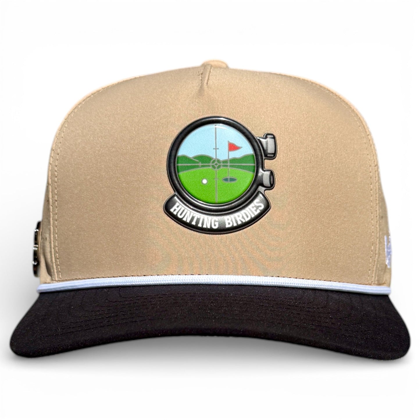 The Logie Joe's Golf Hunting Birdies Snapback Cap is adjustable in tan and black, featuring a round golf course emblem with a red flag, “HUNTING BIRDIES” text, a black brim with white stripe, and built-in magnetic ball marker with marker included.