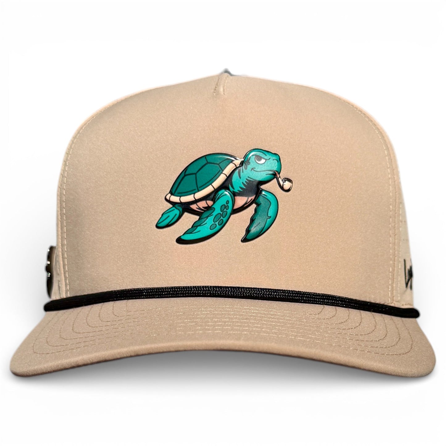The Salty Turtle Golf Hat by Logie Joe's Golf is a beige snapback featuring a cartoon sea turtle with a pipe, black rope detail, and built-in magnetic ball marker holder—adjustable to fit all and includes marker.