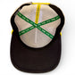 The image shows the inside of Logie Joe's Golf Banana Hammock Snapback Cap, featuring a black brim, yellow edge, green and yellow inner seams with MAKE YOUR MARK and Lays x Sada text, plus a built-in magnetic golf ball marker holder.