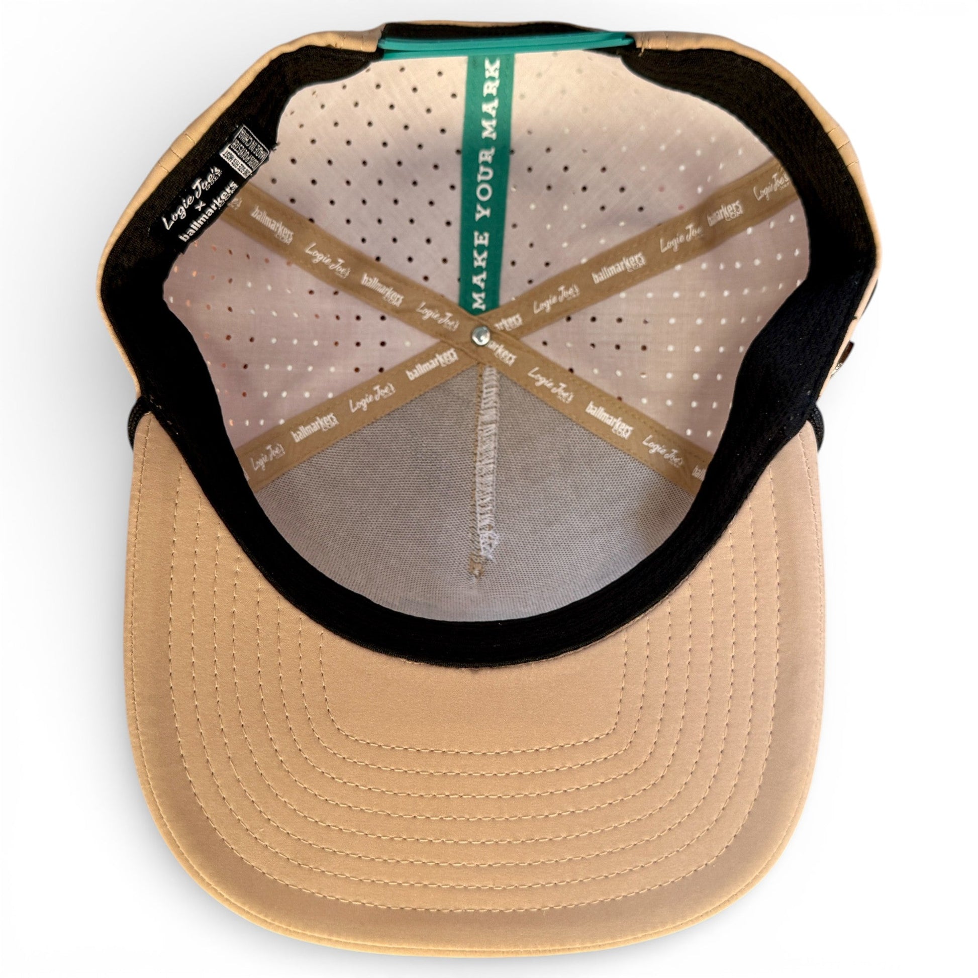 A top-down view of the Salty Turtle Golf Hat by Logie Joe's Golf shows its perforated lining, stitched sweatband, beige brim, and a green “MAKE YOUR MARK” strip at the back that cleverly holds the built-in magnetic ball marker (included).