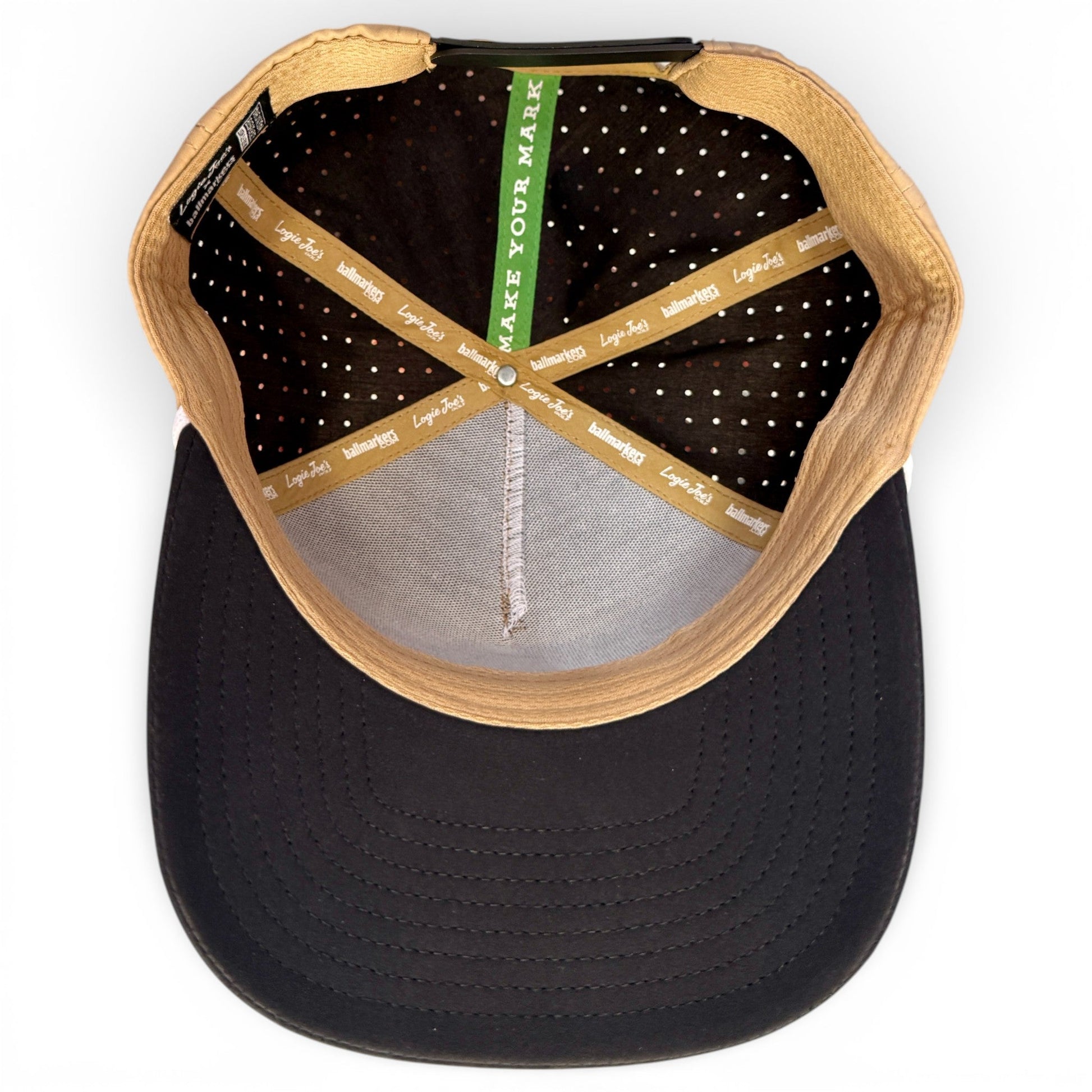 Top-down view of Logie Joe’s Golf Hunting Birdies Snapback Hat in tan and black, featuring a built-in magnetic ball marker holder with marker, adjustable fit, ventilation perforations, and interior taping reading “MAKE YOUR MARK” and “Legacy 100.”.
