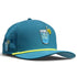 Introducing the Water Hazard Golf Hat by Logie Joe’s Golf—a teal snapback cap with a yellow brim stripe, featuring a playful graphic of a blue iced drink with lemon and straw on the front and a coordinating mini drink motif on the side. Designed for both style and function, this adjustable hat includes a built-in magnetic ball marker holder (plus marker), making it perfect for days on or off the course.