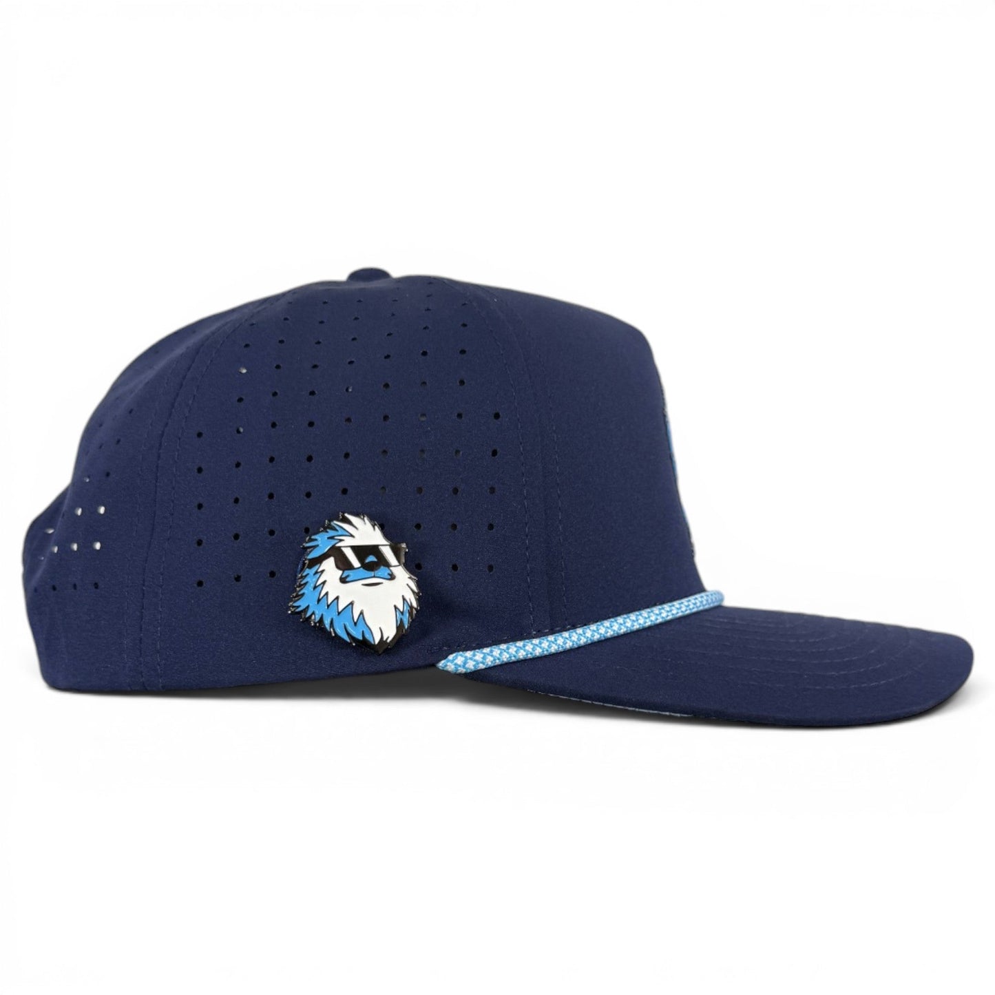 Introducing the Zero Chill Yeti Golf Hat from Logie Joe’s Golf—a navy snapback cap featuring a light blue patterned rope across the brim and a stylish blue-and-white abominable snowman pin on the side. This breathable, adjustable golf hat includes a built-in magnetic ball marker holder with marker for added convenience on the course.